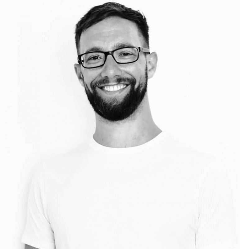 Ben, the CEO of Geeky Tech, smiling and wearing black glasses and a white t-shirt - example of alt text